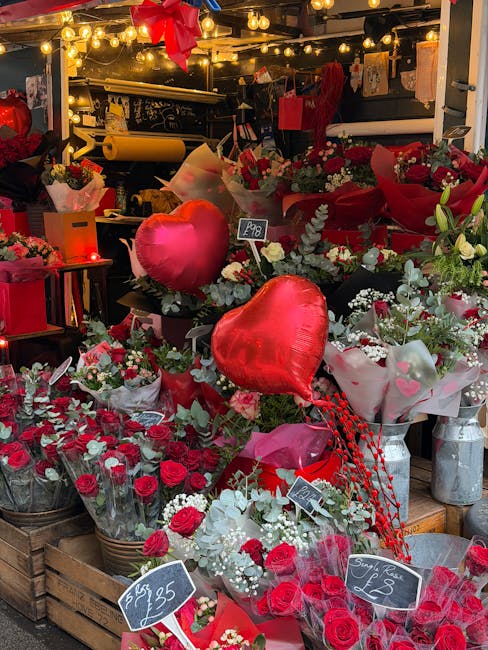 A vibrant display of floral arrangements at the floristfeltham.co.uk shop, featuring a variety of bouquets predominantly in shades of red, pink, and white. The scene includes roses, white gypsophila, 